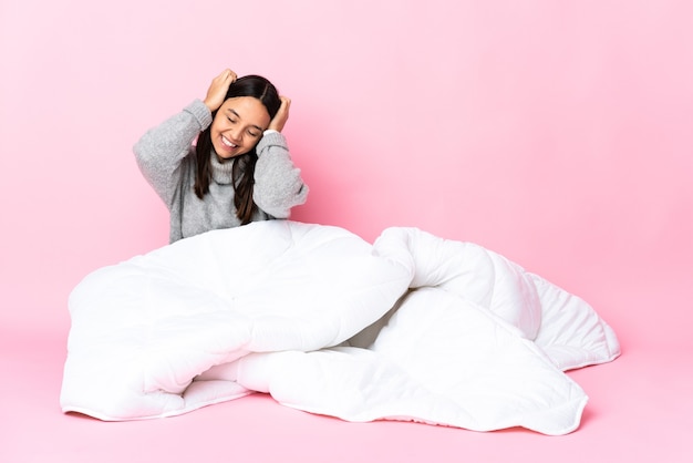 Jovem mestiça de pijama sentada no chão rindo