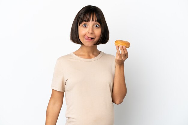 Jovem mestiça grávida isolada no fundo branco segurando uma rosquinha