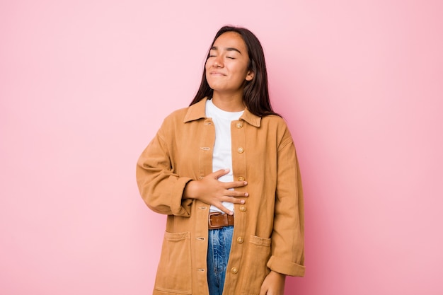 Jovem mestiça indiana isolada toca a barriga, sorri suavemente, comendo e conceito de satisfação.