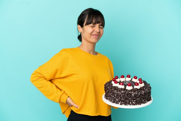 Jovem mestiça segurando bolo de aniversário com dor nas costas por ter feito esforço