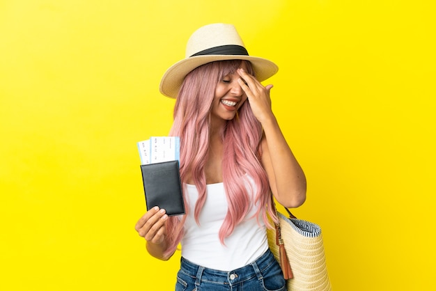 Jovem mestiça segurando passaporte e bolsa de praia isolados em um fundo amarelo percebeu algo e tem a intenção de encontrar a solução