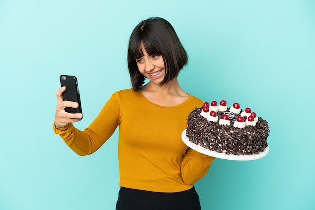 Foto jovem mestiça segurando um bolo de aniversário fazendo uma selfie