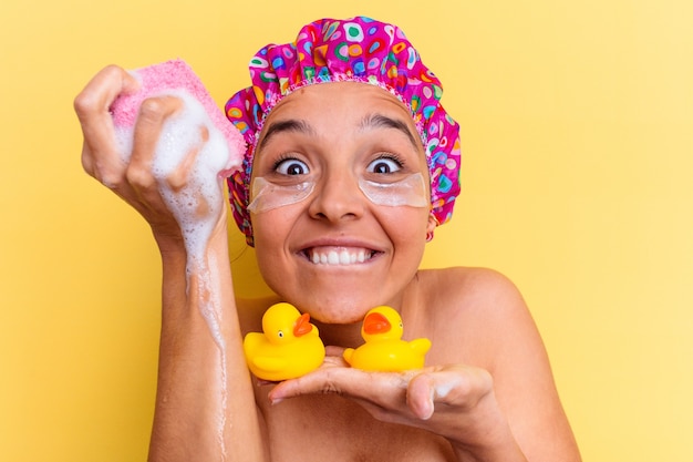 Foto jovem mestiça tomando banho segurando uma esponja e patos de borracha