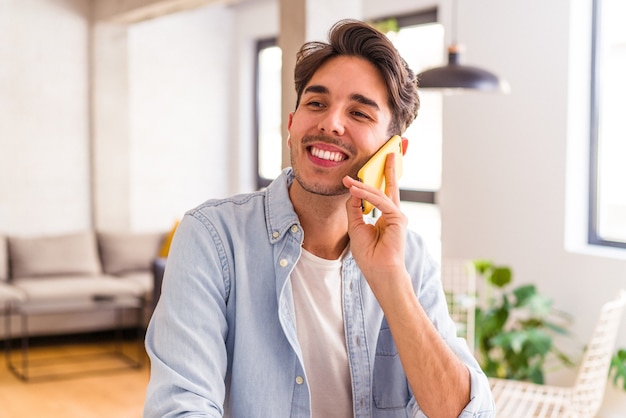 Jovem mestiço falando ao telefone em uma cozinha