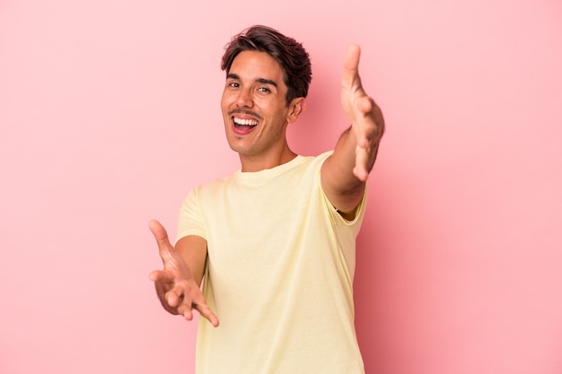 Jovem mestiço isolado no fundo branco se sente confiante em dar um abraço para a câmera.