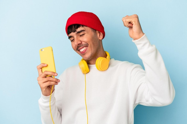 Jovem mestiço ouvindo música isolada em fundo azul