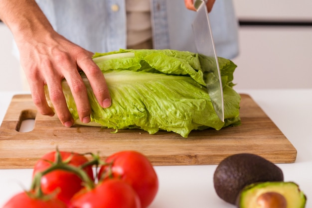 Jovem mestiço preparando uma salada para o almoço