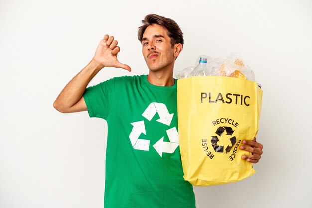 Jovem mestiço reciclando plástico isolado em um fundo amarelo sente-se orgulhoso e autoconfiante, exemplo a seguir.