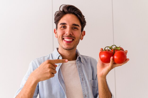 Jovem mestiço segurando tomates na cozinha