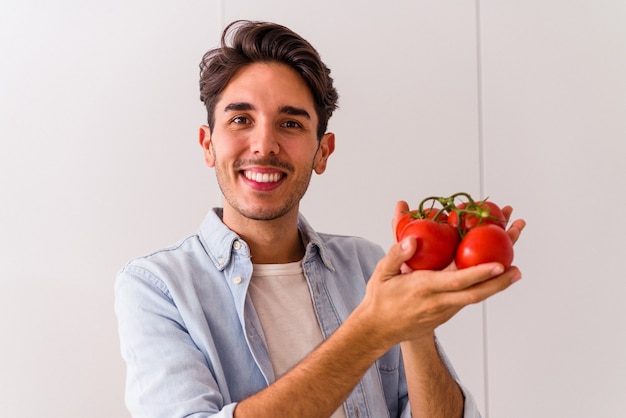 Jovem mestiço segurando tomates na cozinha