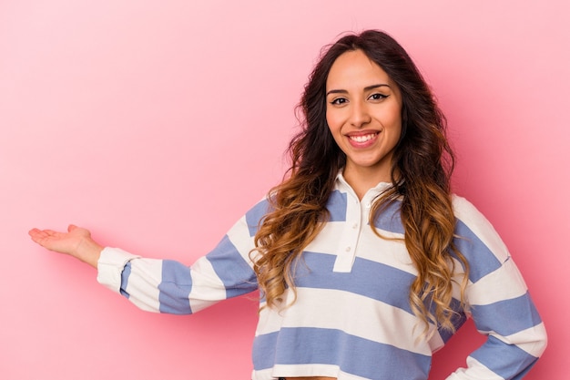 Jovem mexicana isolada em um fundo rosa, mostrando uma expressão de boas-vindas.