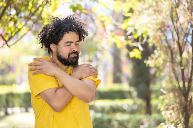 Jovem mexicano com barba e afro se abraçando conceito de amor próprio