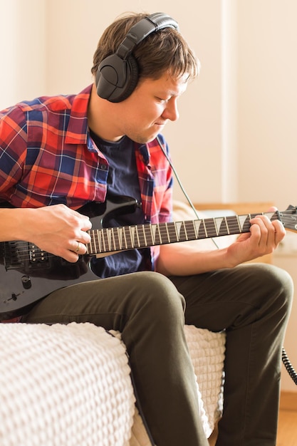 Jovem milenar, cara tocando guitarra elétrica. Fique em casa, atividade em casa, aulas de aprendizagem