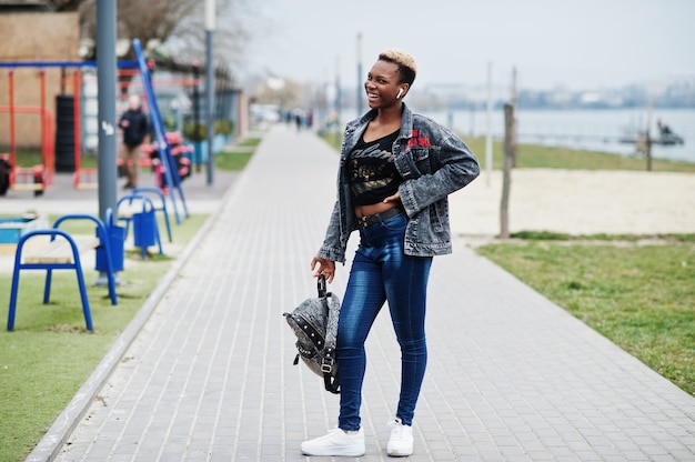 Jovem milenar garota afro-americana na cidade. mulher negra feliz com fones de ouvido sem fio. conceito da geração z.