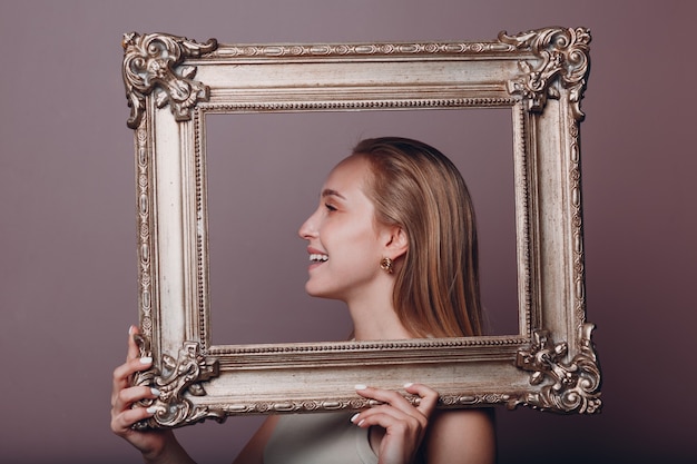 Foto jovem milenar loira segurando uma moldura dourada no retrato de rosto de mãos