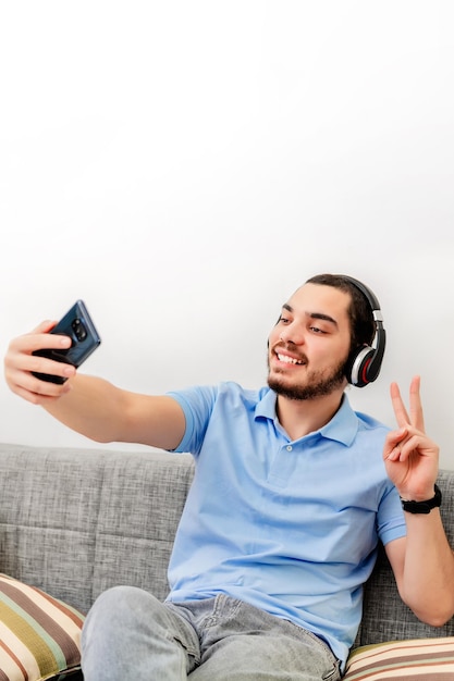 Jovem milenar tirando uma selfie sorrindo para a câmera na sala de estar em casa