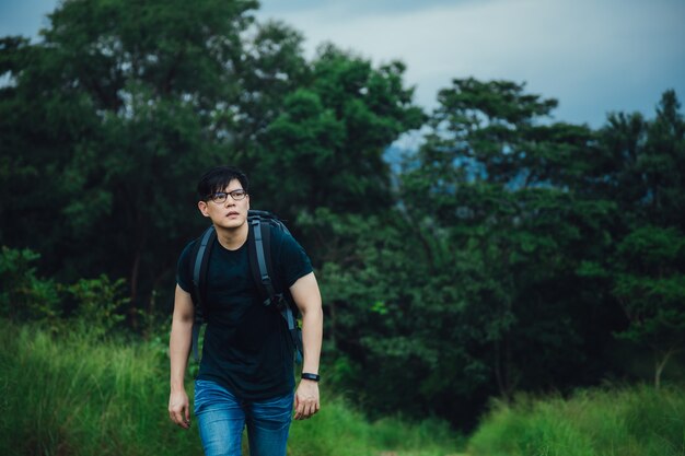 Jovem mochileiro com mochila viajando na floresta. Caminhadas turísticas na floresta da selva.