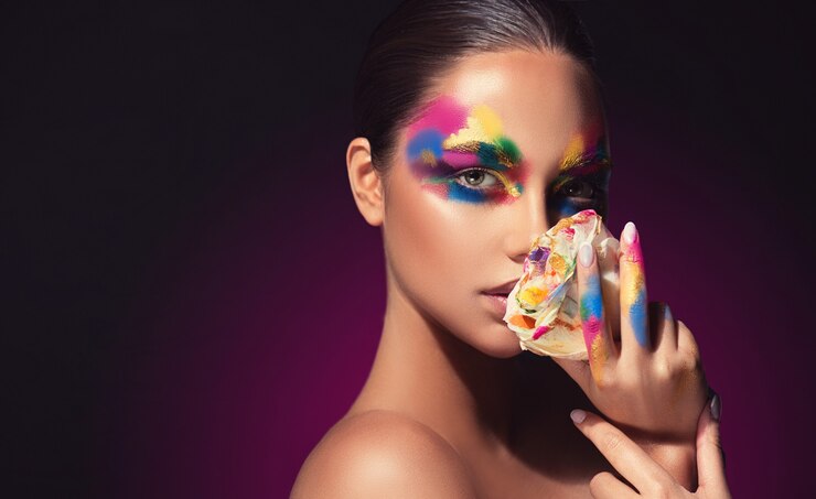 Jovem modelo atraente com paleta de tons no rosto segurando rosa com pétalas coloridas Maquiagem
