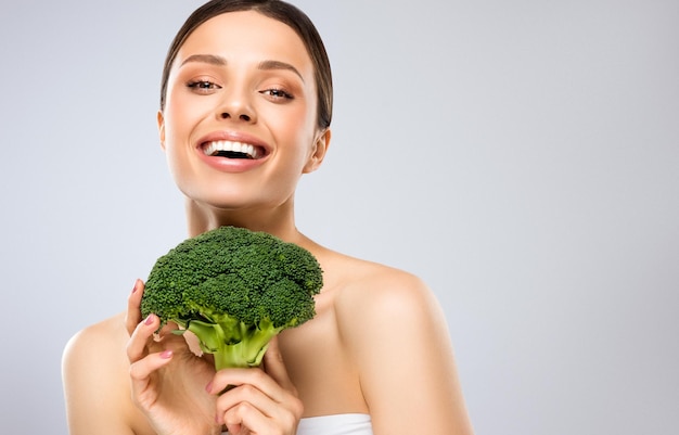Foto jovem modelo com o vegetal mulher rindo bonita segurando brócolis verde fresco nas mãos
