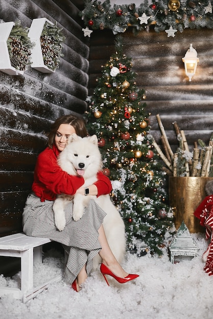 Jovem modelo com sapatos vermelhos e saia xadrez posando com cachorro fofo Samoyed