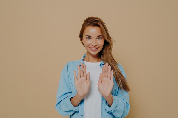 Jovem modelo feminina sorridente com cabelo comprido e liso e uma camisa azul grande