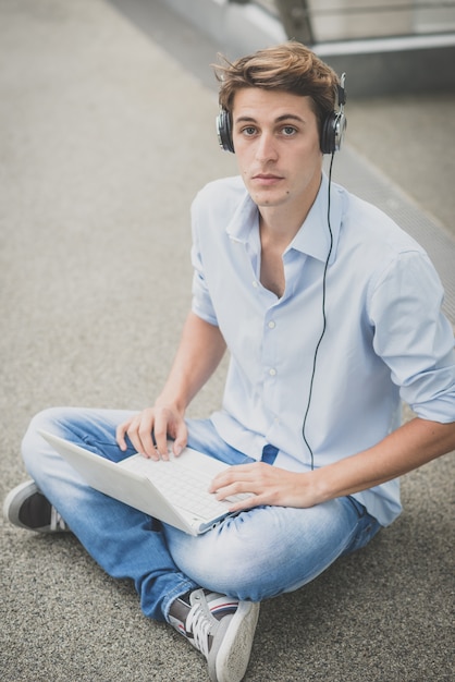 Jovem modelo hansome homem loiro com notebook e fones de ouvido