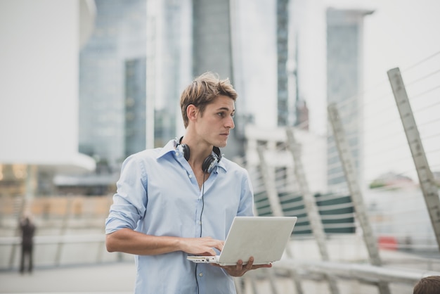 jovem modelo hansome homem loiro com notebook e fones de ouvido