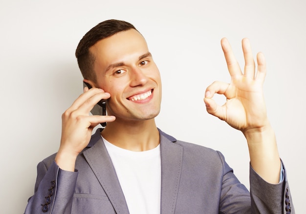 Jovem moderno falando no celular, sobre uma superfície branca