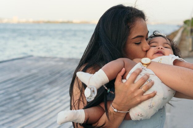 Jovem Mon levanta seu bebê no ar e sorri para ele