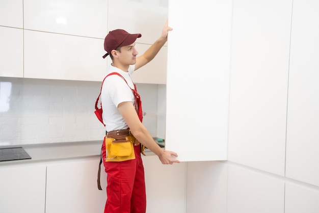 Jovem montando móveis de cozinha.