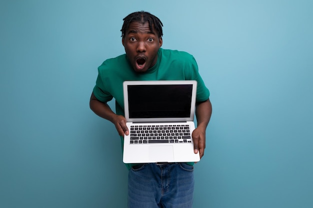 Jovem morena americana em camiseta casual mostra tela de laptop com maquete para página da web