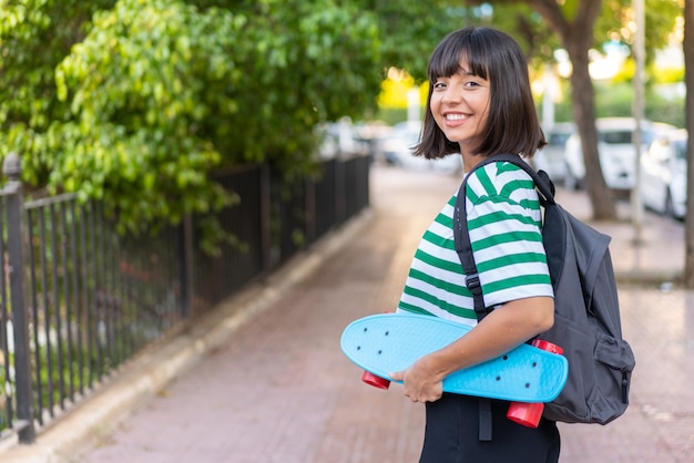 Jovem morena ao ar livre com um skate