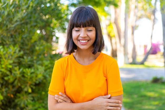 Jovem morena ao ar livre em um parque Com uma expressão feliz