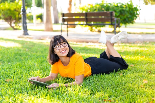 Jovem morena ao ar livre segurando um tablet