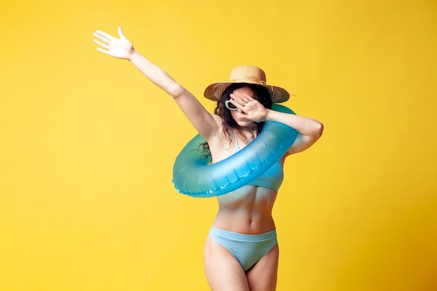 Jovem morena atraente em maiô azul com danças de anel inflável nadando