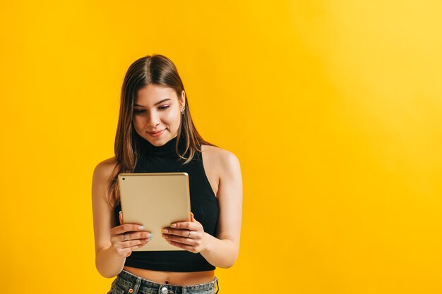 Jovem morena atraente usando um tablet e sorrindo