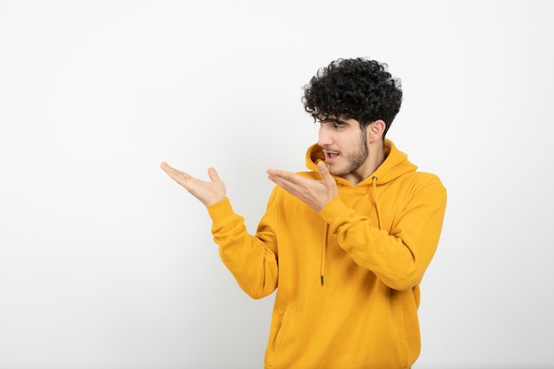 jovem morena com capuz amarelo em pé e posando.