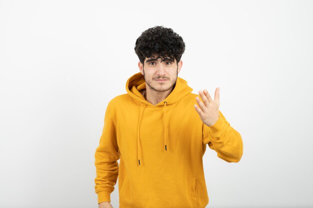 jovem morena com capuz amarelo em pé e posando.