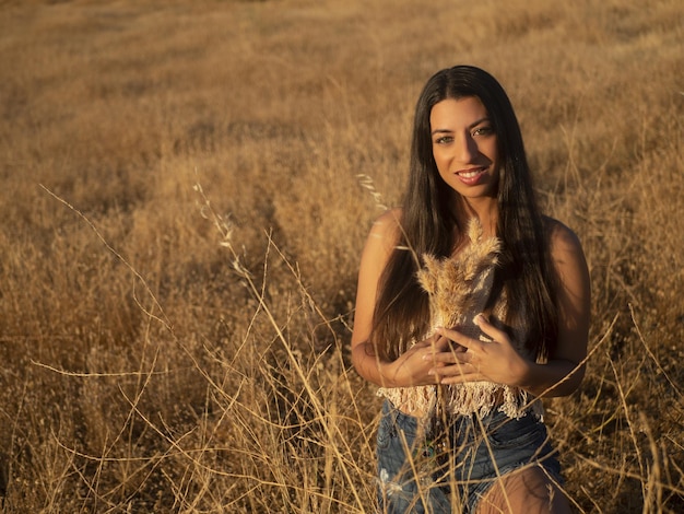 Jovem morena com grama seca em campo