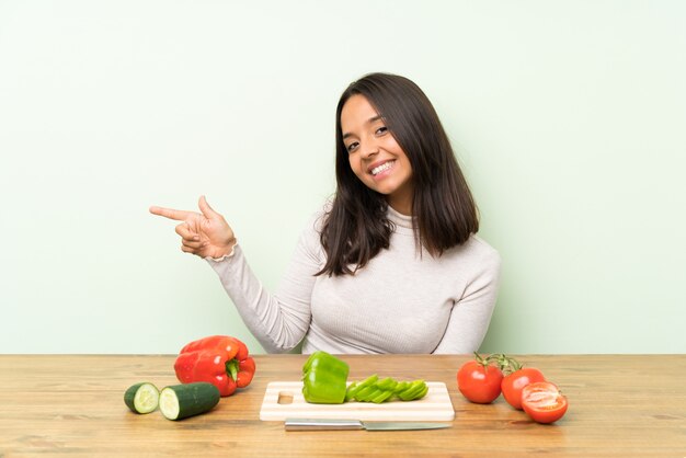 Jovem morena com legumes, apontando o dedo para o lado