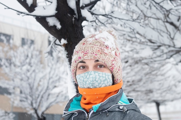 Jovem morena com roupas de inverno e máscara protetora na neve