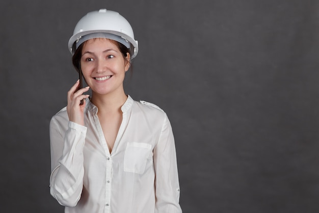 Foto jovem morena com um capacete protetor falando ao telefone, copyspace