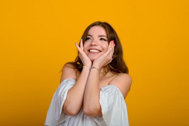 Jovem morena com um sorriso e grandes olhos surpresos posando.