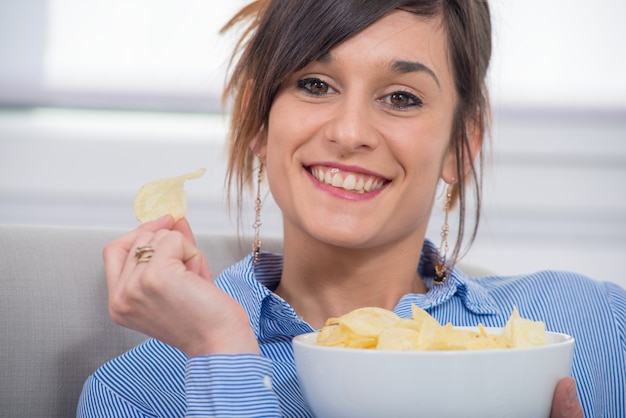 Jovem morena comendo batatas fritas