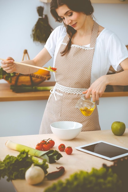 Jovem morena cozinhando na cozinha. Dona de casa segurando a colher de pau na mão. Conceito de comida e saúde.