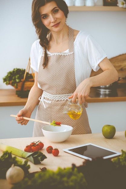 Jovem morena cozinhando na cozinha. Dona de casa segurando a colher de pau na mão. Conceito de comida e saúde.