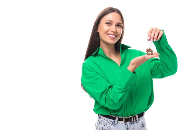 jovem morena europeia sorridente com olhos castanhos em uma blusa verde segurando o chaveiro de sua casa