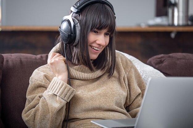 Jovem morena linda sorrindo com um suéter aconchegante e olhando para a tela do laptop. o conceito de treinamento online, trabalho remoto, comunicação por vídeo.