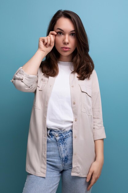 Jovem morena muito europeia de camisa e jeans em fundo azul