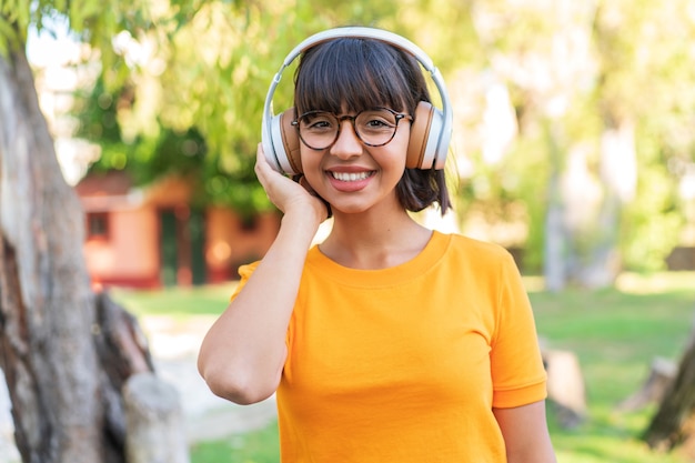 Jovem morena no parque ouvindo música